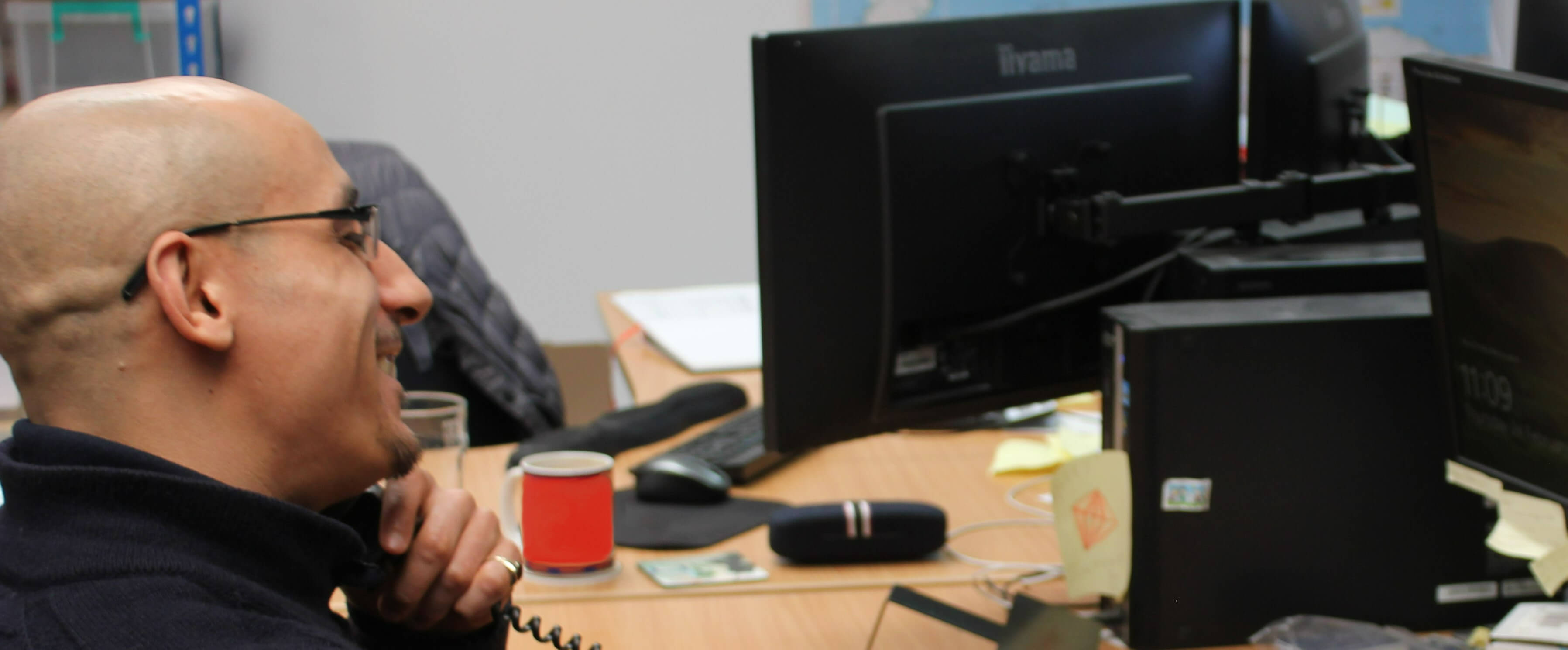 Profile of a man wearing glasses, smiling and chatting on the phone in an office to help illustrate GB Electronics' sales services.